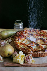 Photo of a delicious, homemade and fresh baked rustic curd pie with pears and cinnamon on wooden table on black background indoor rustic style
