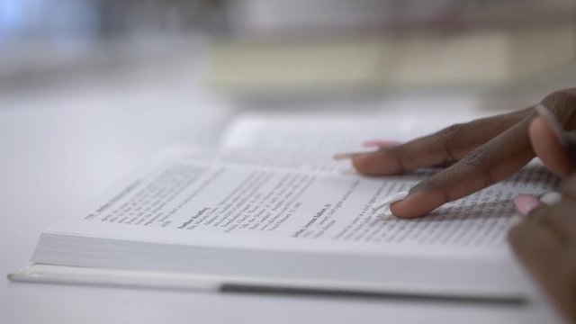 Girl skimming through book at library with finger 4k