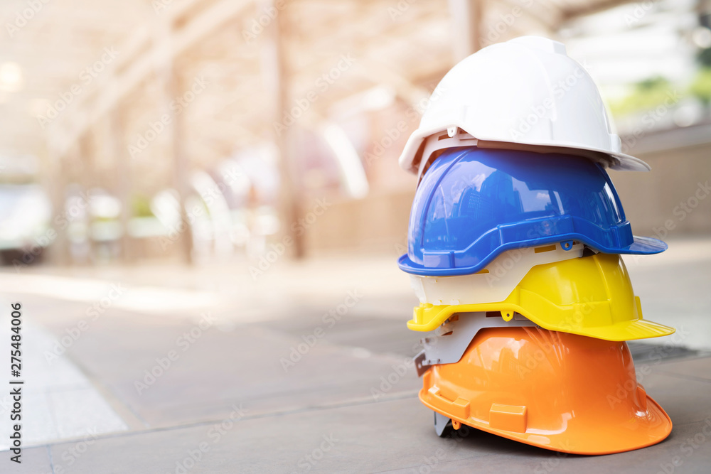 Wall mural orange, yellow, blue and white hard safety wear helmet hat in the project at construction site build