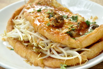 fried egg stuffed mussel with bean sprout topping garlic and dressing chili sauce on plate
