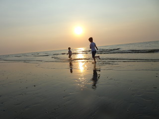 Zwei Kinder laufen am Strand im Wasser 1