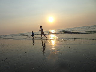 Zwei Kinder laufen am Strand im Wasser 2