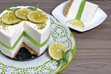 Lime cheesecake without baking. Decorated with lime slices. The piece is cut off. Lies on a plate.