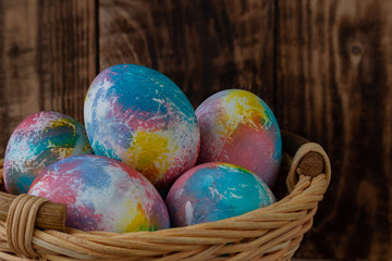 Colorful Easter eggs in a basket on a wooden background