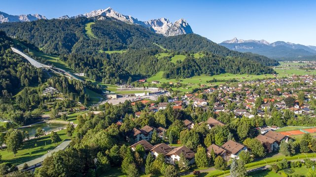 View over a green alpine valley with villages and the olympia ski jump