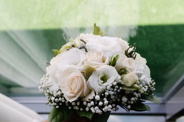 White bouquet of flowers standing in a vase on the window