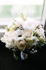 White bouquet of flowers standing in a vase on the window