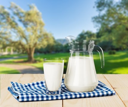 Glass of milk and jug on blurred background