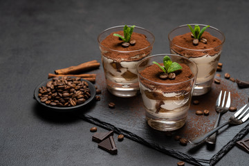 Classic tiramisu dessert in a glass on stone serving board on dark concrete background