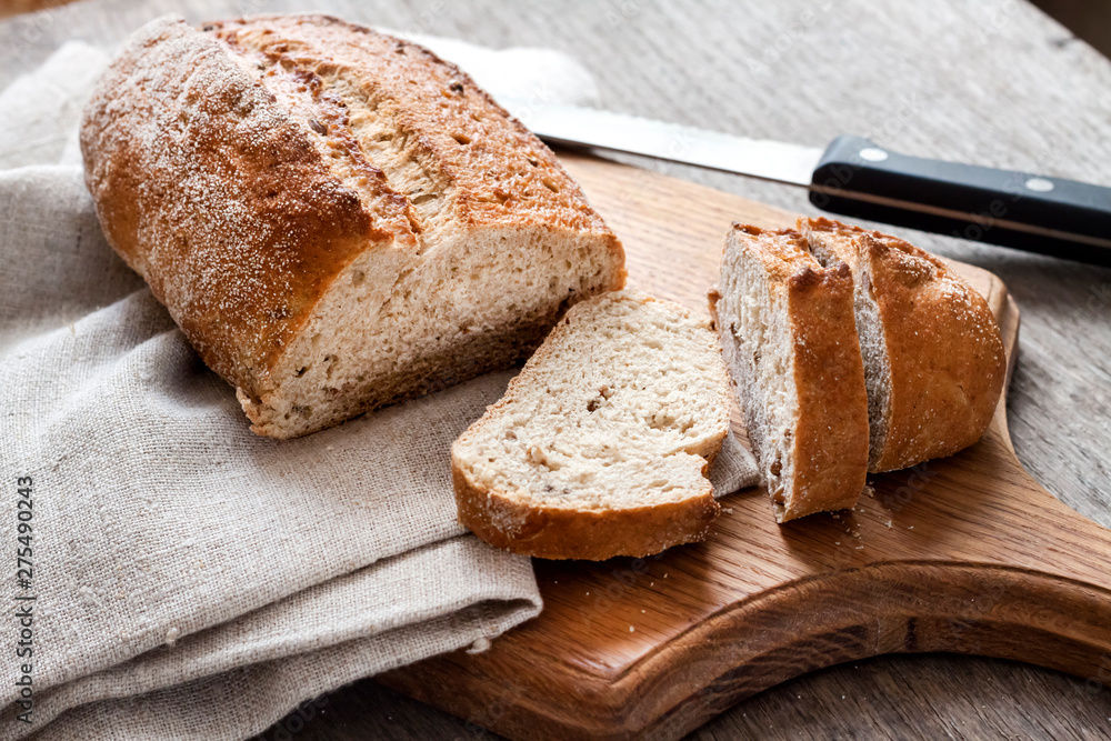 Wall mural loaf of whole wheat bread with slices on wooden board