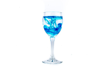 Blue food coloring diffuse in water inside wine glass with empty copyspace area for slogan or advertising text message, over isolated white background.