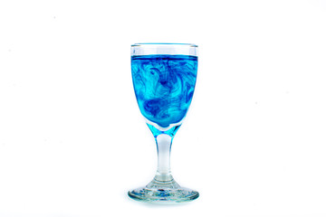 Blue food coloring diffuse in water inside wine glass with empty copyspace area for slogan or advertising text message, over isolated white background.