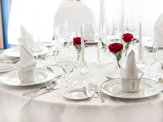 wedding table. noble wine glasses and roses decorating white clean table