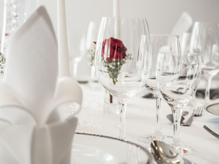 wedding table. noble wine glasses and roses decorating white clean table