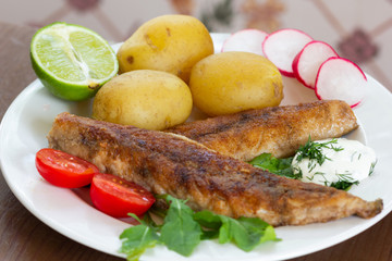 Fried  mackerel with potato boiled with skin on and vegetables and lime on garnish with white sauce