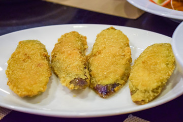 Tasty fried breaded eggplant on white plate in restaurant