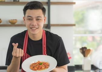 Young happy Asian man holding and present a delicious healthy spaghetti tomato sauce