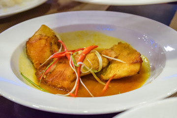 Fried piece of meat with red bell pepper on whate plate