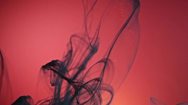 Black nacreous paint in water against red background.
