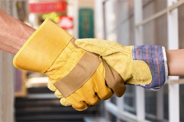 Building, teamwork, partnership, gesture and people concept - close up of builders hands in gloves...