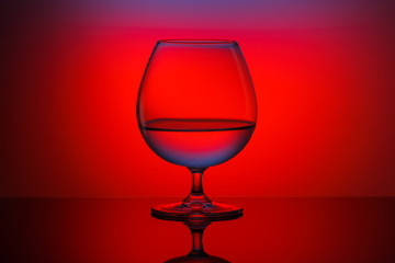 Fototapeta na wymiar One glass on the table on a multi-colored background