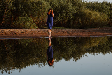 Fototapeta na wymiar beautiful girl reflected in the mirror of a pond on a summer evening