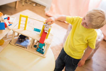 Junge spielt mit Puppenhaus