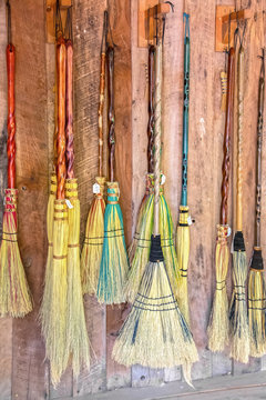 Brooms for sale - variety of decorative brooms that look like they are made for witches and wizards and flying hanging against wooden wall with price tags on them