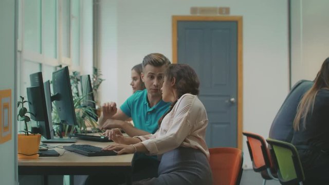 Young woman consulting with colleague about work. Pretty lady looking in pc