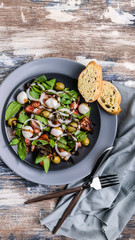 Top view tasty salad from fresh herbs with mozzarella, tomatoes, olives and onions. Mediterranean traditional cuisine. Vertical shot