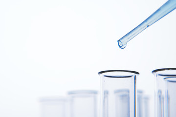 Pipette dropping liquid into glass tubes