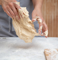 Mistress kneads the dough in the kitchen