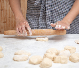 Girl rolls the dough in the kitchen