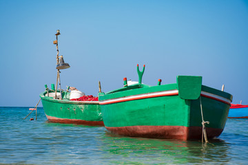 Fototapeta na wymiar Couple of beautiful old colored green and red fishing wooden boats on the water