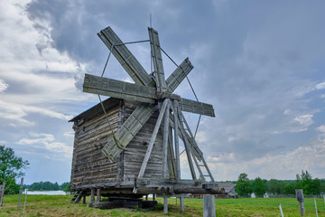 Fototapeta na wymiar Scenic view of small wooden windmill on Kizhi island on Onezhsky lake in Russian Federation. Beautiful summer sunny look of traditional industrial building of russian North in Karelia