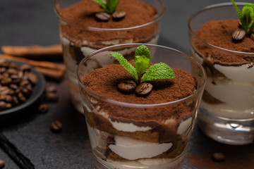 Classic tiramisu dessert in a glass on stone serving board on dark concrete background