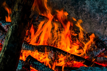 Charred wood and bright flames on dark background