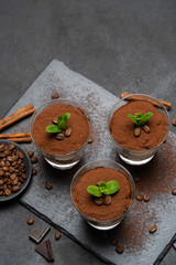 Classic tiramisu dessert in a glass on stone serving board on dark concrete background