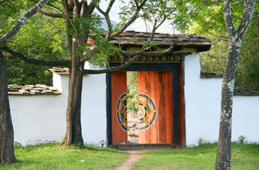 Eingangstor zu einem Kloster im Königreich Bhutan im Himalaya, Asien. Es ist leicht geöffnet mit...
