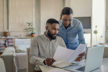 Young African American couple doing online banking at home