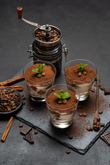 Classic tiramisu dessert in a glass on stone serving board on dark concrete background