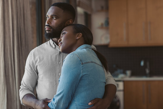 African American Couple Hugging And Looking Out Of Their Window