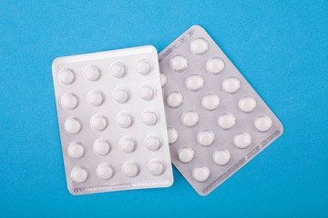 White pills in blister on an blue background. The concept of antidepressants and healing