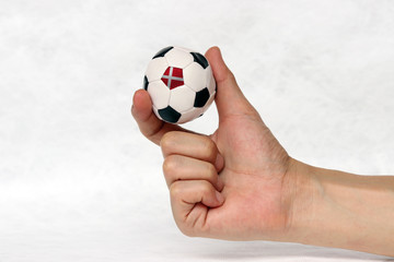Fototapeta premium Mini ball of football in hand, hold it with two finger on white background. Concept of sport or the game in handle or minor matter.