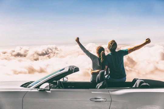 Happy car road trip couple freedom on summer travel vacation driving convertible sports car feeling excited winning free.