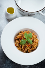 White plate with italian fregola pasta, high angle view over grey stone surface, vertical shot
