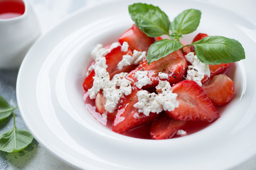 Strawberry dessert with addition of cottage cheese and sauce served in a white plate, close-up