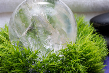 Wellness Relax concept with Spa elements. Rolled White Towels, Basalt Stones, Lemurian Clear Quartz Sphere and Dianthus Flowers on purple background.