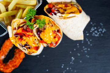Burritos wraps with beef and vegetables on a black background