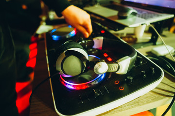 control DJ for mixing music with blurred people dancing at party in nightclub